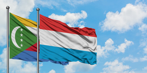 Comoros and Luxembourg flag waving in the wind against white cloudy blue sky together. Diplomacy concept, international relations.