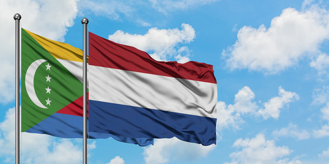 Comoros and Netherlands flag waving in the wind against white cloudy blue sky together. Diplomacy concept, international relations.
