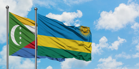 Comoros and Rwanda flag waving in the wind against white cloudy blue sky together. Diplomacy concept, international relations.