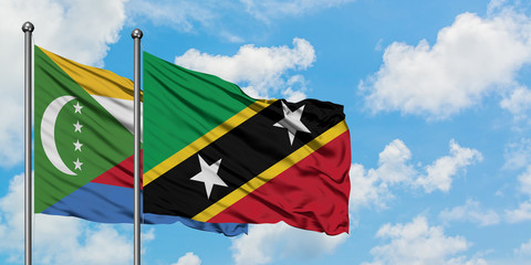 Comoros and Saint Kitts And Nevis flag waving in the wind against white cloudy blue sky together. Diplomacy concept, international relations.