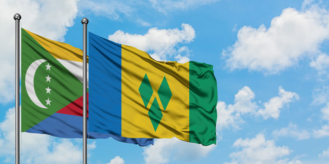 Comoros and Saint Vincent And The Grenadines flag waving in the wind against white cloudy blue sky...