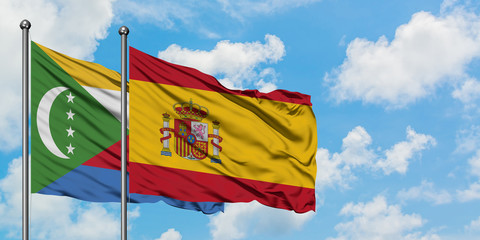 Comoros and Spain flag waving in the wind against white cloudy blue sky together. Diplomacy concept, international relations.