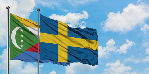 Comoros and Sweden flag waving in the wind against white cloudy blue sky together. Diplomacy concept, international relations.