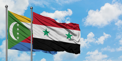 Comoros and Syria flag waving in the wind against white cloudy blue sky together. Diplomacy...