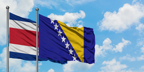 Costa Rica and Bosnia Herzegovina flag waving in the wind against white cloudy blue sky together. Diplomacy concept, international relations.