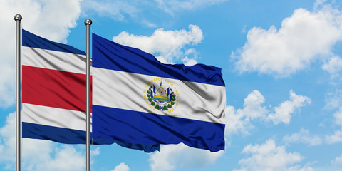 Costa Rica and El Salvador flag waving in the wind against white cloudy blue sky together. Diplomacy concept, international relations.
