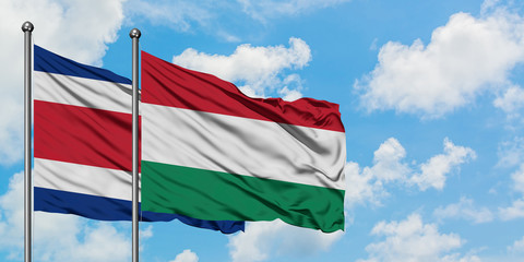 Costa Rica and Hungary flag waving in the wind against white cloudy blue sky together. Diplomacy concept, international relations.