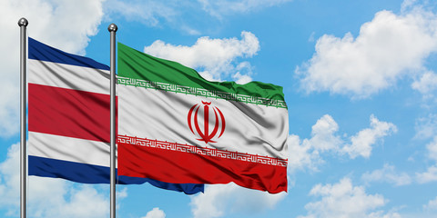 Costa Rica and Iran flag waving in the wind against white cloudy blue sky together. Diplomacy concept, international relations.