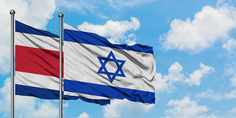 Costa Rica and Israel flag waving in the wind against white cloudy blue sky together. Diplomacy concept, international relations.