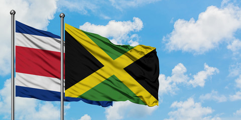 Costa Rica and Jamaica flag waving in the wind against white cloudy blue sky together. Diplomacy concept, international relations.