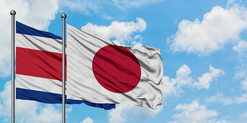 Costa Rica and Japan flag waving in the wind against white cloudy blue sky together. Diplomacy concept, international relations.