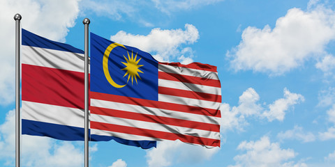 Costa Rica and Malaysia flag waving in the wind against white cloudy blue sky together. Diplomacy concept, international relations.