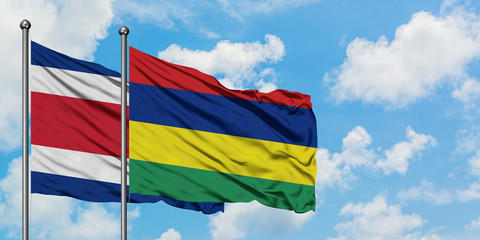 Costa Rica and Mauritius flag waving in the wind against white cloudy blue sky together. Diplomacy concept, international relations.