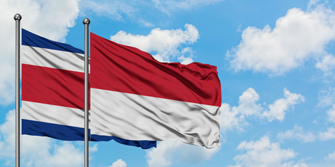 Costa Rica and Monaco flag waving in the wind against white cloudy blue sky together. Diplomacy concept, international relations.