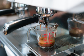 Coffee in measuring cup on a coffee machine