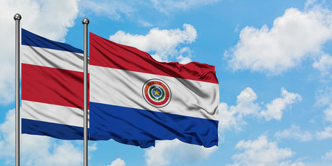 Costa Rica and Paraguay flag waving in the wind against white cloudy blue sky together. Diplomacy concept, international relations.