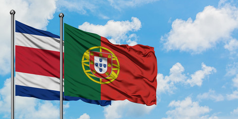 Costa Rica and Portugal flag waving in the wind against white cloudy blue sky together. Diplomacy concept, international relations.
