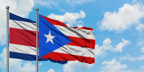 Costa Rica and Puerto Rico flag waving in the wind against white cloudy blue sky together. Diplomacy concept, international relations.