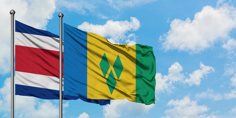 Costa Rica and Saint Vincent And The Grenadines flag waving in the wind against white cloudy blue...