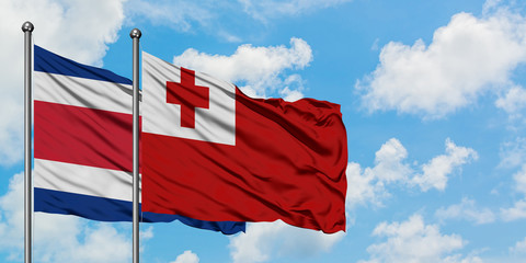 Costa Rica and Tonga flag waving in the wind against white cloudy blue sky together. Diplomacy concept, international relations.