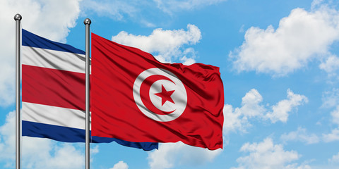 Costa Rica and Tunisia flag waving in the wind against white cloudy blue sky together. Diplomacy concept, international relations.