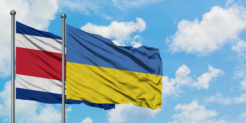Costa Rica and Ukraine flag waving in the wind against white cloudy blue sky together. Diplomacy concept, international relations.