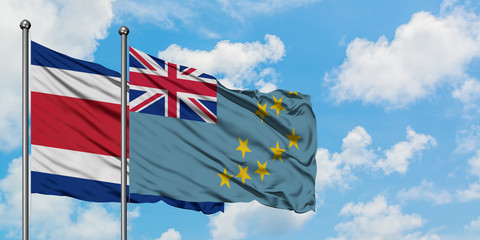 Costa Rica and Tuvalu flag waving in the wind against white cloudy blue sky together. Diplomacy...