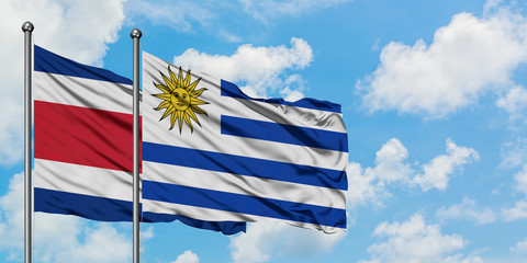 Costa Rica and Uruguay flag waving in the wind against white cloudy blue sky together. Diplomacy concept, international relations.