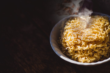 The smoke was poured from the boiled instant yellow noodles that had been boiled in hot water and brought out from a boiling pot in a bowl to be prepared as a food menu.