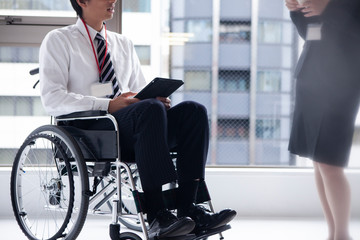 女性社員と会話をする車椅子のビジネスマン
