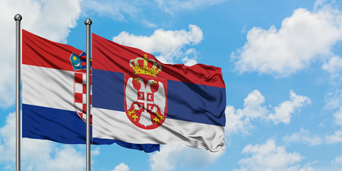 Croatia and Serbia flag waving in the wind against white cloudy blue sky together. Diplomacy concept, international relations.
