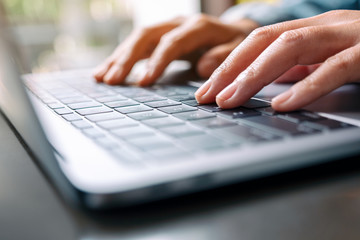 Closeup image of a woman working and typing on laptop computer on the table