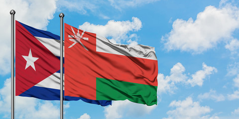 Cuba and Oman flag waving in the wind against white cloudy blue sky together. Diplomacy concept, international relations.