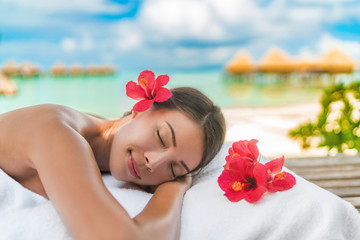 Luxury hotel spa massage table Asian woman relaxing on exotic travel vacation on beach. Summer pampering lifestyle skincare body care.