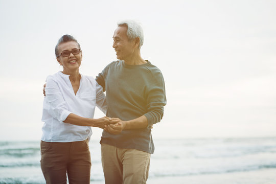 Senior Couple Walking On The Beach In Fall Season