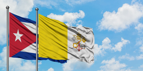 Cuba and Vatican City flag waving in the wind against white cloudy blue sky together. Diplomacy...