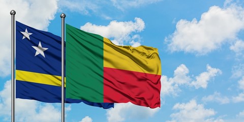 Curacao and Benin flag waving in the wind against white cloudy blue sky together. Diplomacy concept, international relations.