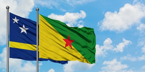Curacao and French Guiana flag waving in the wind against white cloudy blue sky together. Diplomacy concept, international relations.