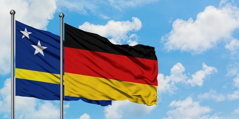 Curacao and Germany flag waving in the wind against white cloudy blue sky together. Diplomacy concept, international relations.