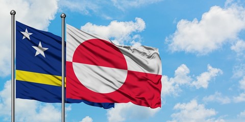 Curacao and Greenland flag waving in the wind against white cloudy blue sky together. Diplomacy concept, international relations.