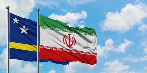 Curacao and Iran flag waving in the wind against white cloudy blue sky together. Diplomacy concept, international relations.