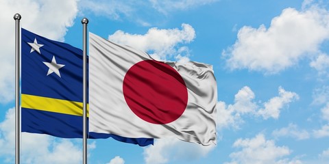 Curacao and Japan flag waving in the wind against white cloudy blue sky together. Diplomacy concept, international relations.