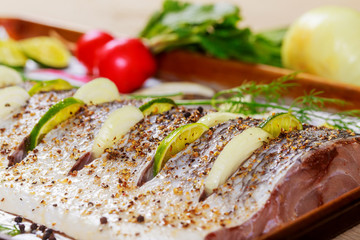 Raw Marinated fish fillet with onions, on baking tray with at oven ready to cook.