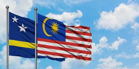 Curacao and Malaysia flag waving in the wind against white cloudy blue sky together. Diplomacy concept, international relations.