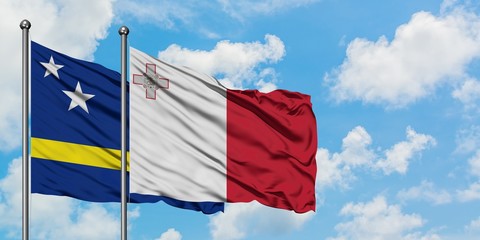 Curacao and Malta flag waving in the wind against white cloudy blue sky together. Diplomacy concept, international relations.