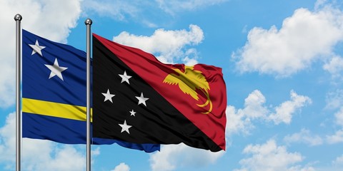 Curacao and Papua New Guinea flag waving in the wind against white cloudy blue sky together. Diplomacy concept, international relations.
