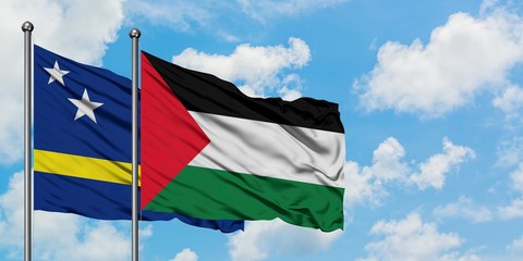 Curacao and Palestine flag waving in the wind against white cloudy blue sky together. Diplomacy concept, international relations.