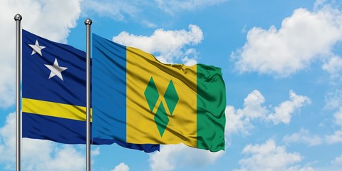 Curacao and Saint Vincent And The Grenadines flag waving in the wind against white cloudy blue sky...