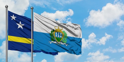 Curacao and San Marino flag waving in the wind against white cloudy blue sky together. Diplomacy concept, international relations.