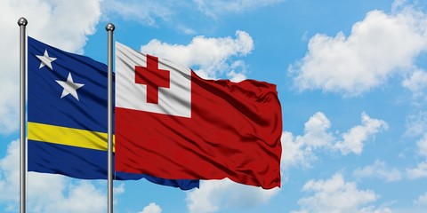 Curacao and Tonga flag waving in the wind against white cloudy blue sky together. Diplomacy concept, international relations.